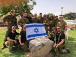 Group of IDF soldiers holding Israeli flag outside