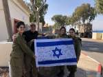 Civilian with three female IDF soldiers holding signed Israeli flag