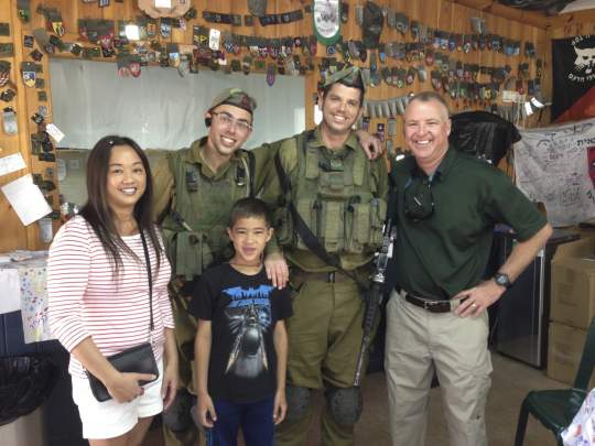 Two IDF soldiers indoors alongside a man, woman and child
