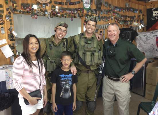 Two IDF soldiers indoors alongside a man, woman and child