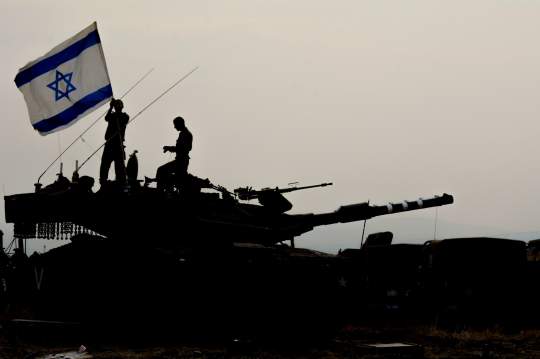 waving the Israeli flag standing on a tank